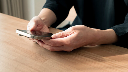 リラックスする男性の手元 スマートフォンとコーヒー ライフスタイル / Man using smartphone on wooden table, relaxed lifestyle