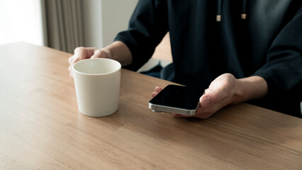 リラックスする男性の手元 スマートフォンとコーヒー ライフスタイル / Man using smartphone on wooden table, relaxed lifestyle