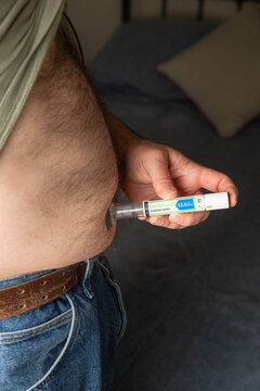 Greeneville, TN, USA-February 16, 2026:  Man using an injector pen to administer Zepbound into abdomen.
