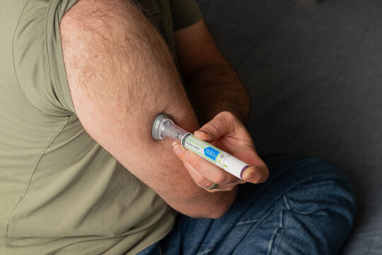 Greeneville, TN, USA-February 16, 2026:  Man using an injector pen to administer Zepbound into abdomen.