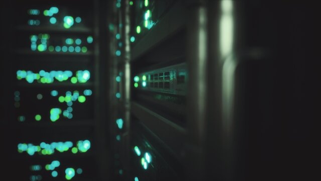 In a dark server room, colorful lights flicker and glow from rows of digital equipment. The atmosphere feels alive with the hum of technology and the pulse of data flowing through wires.