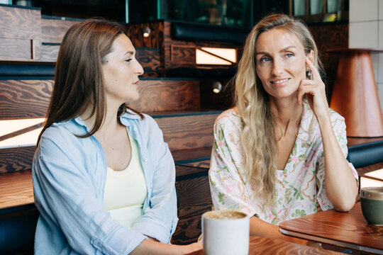 Two women friends sitting in a cafe talking and drinking coffee.