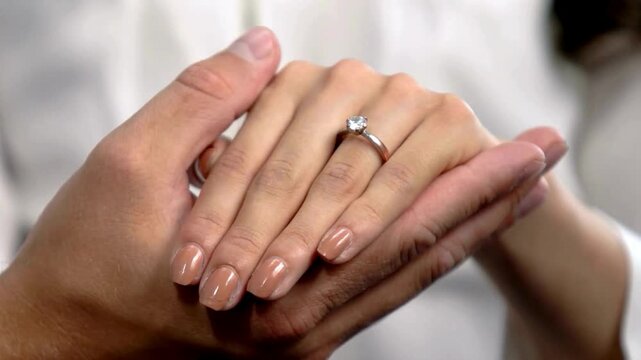 Beautiful shot of a man holding a Girl's hand after putting an engagement ring. classic solitaire diamond ring on lover's finger. bridal boutiques, jewelry advertisements, and romantic storytelling