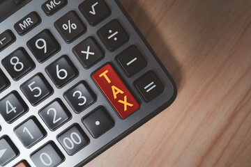 Tax calculation concept with calculator and red tax button on wooden desk background. Financial planning, accounting, income tax payment, business finance and budgeting management theme.