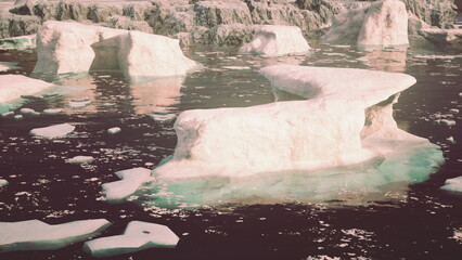 Large ice formations drift gently in a tranquil sea. Shades of blue and white contrast with the dark water, creating a serene scene at dawn in a remote polar landscape. © icetray