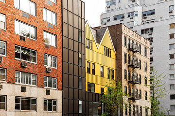 Fototapeta premium New York City apartment buildings with colorful facades and classic fire escapes.