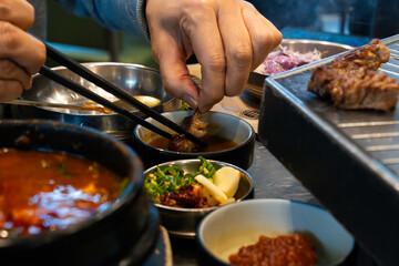 dipping a piece of roasted pork belly into soy sauce