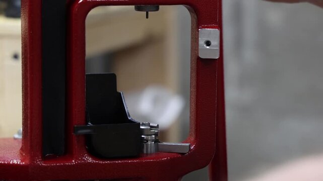 Close-up of a hand operating a reloading press for ammunition manufacturing