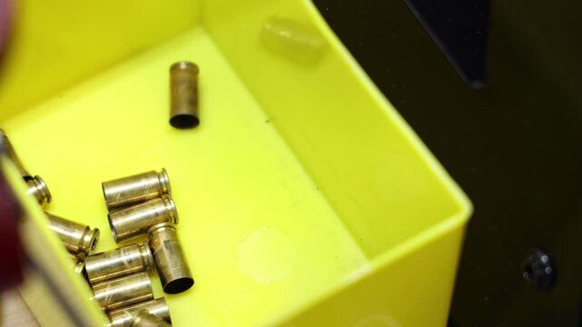 Collection of spent brass shell casings in a bright yellow container for reloading or disposal