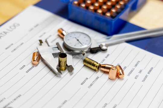 Precision measurement of ammunition components on a data log sheet with calipers and dial indicator