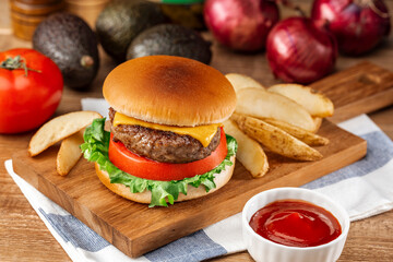 木製ボードにのせたチーズバーガーとフライドポテト