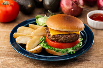 木製テーブルに置かれたハンバーガーとフライドポテト