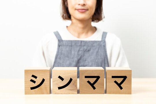 「シンママ」と書かれたブロックとエプロン姿の女性