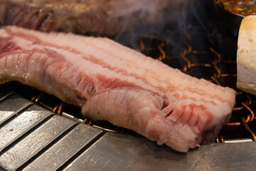 roasting pork belly on charcoal grill in a Korean restaurant