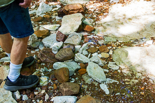 Feet next to colorful river rocks