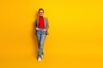 Fototapeta premium Young woman in stylish outfit posing against vibrant yellow background, showcasing casual elegance and youthful style
