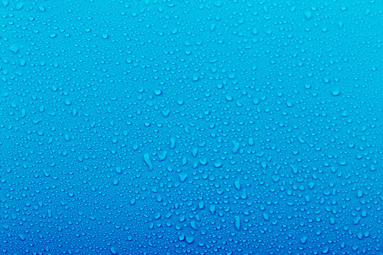 Water droplets on a blue background show textures and patterns created by moisture in the environment during a rainy day