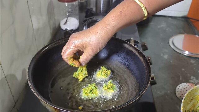 Making Spinach pakoda with mixture of Spinach and Chickpea Flour Batter deep frying in Indian home kitchen 