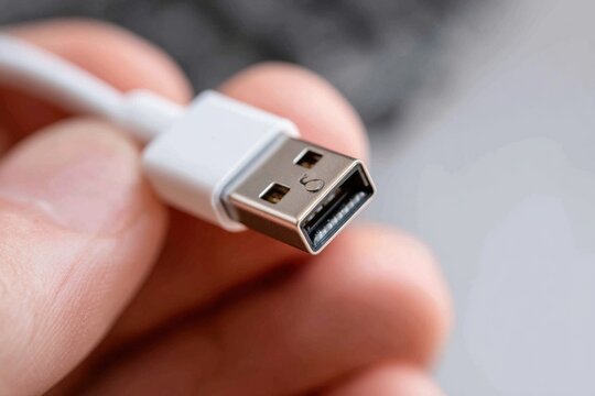 Hand is unplugging a USB connector from a device in an indoor setting during daylight, showing moments of resource cleanup