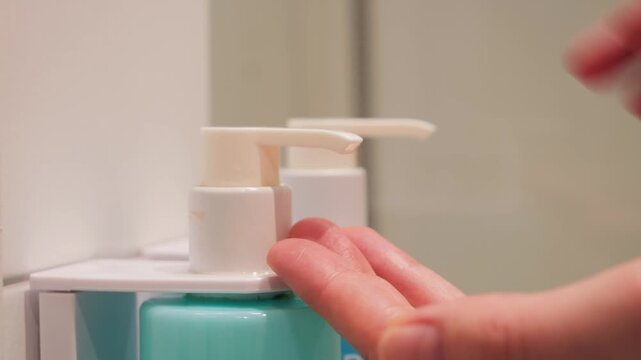 A close-up of a woman's hands squeezing soap from a dispenser in a bathroom. Healthcare and hygiene concept. High quality 4k footage