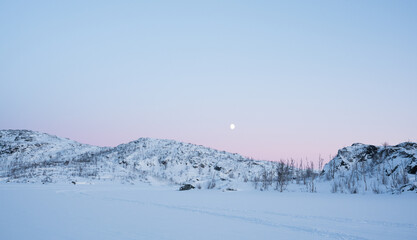 Pink dawn light and a full moon above a winter mountain landscape in the arctic circle in Sweden © Jacob Hall
