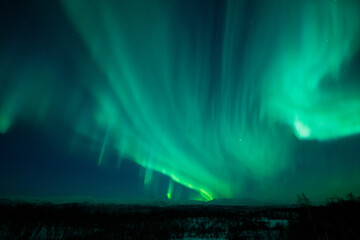 Northern lights explosion in the night sky above the mountains in northern Sweden, a winter scene