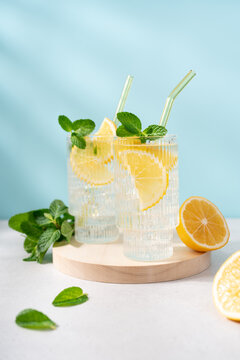 Fresh Lemonade in Tall Glass with Lemon Slice and Mint on Blue Background, Refreshing Summer Drink with Copy Space, Clean Minimal Beverage Concept