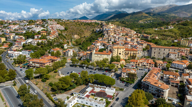 Aerial view of a historic town nestled against a lush hillside. Panorama of Scalea, a town in the province of Cosenza, in Calabria, Southern Italy. The Calabrian Apennines are in the background.