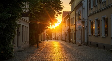 Sunset over european street buildings with warm sunlight illuminating cobblestone path
