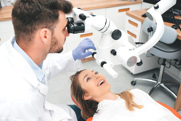 Dentist checking up patient teeth with microscope