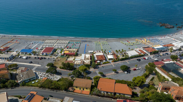 Aerial view of coastal road bordering an organized beach resort. Panorama of the beach of Scalea, in province of Cosenza, Calabria, Italy. The promenade runs along the Tyrrhenian Sea coast.