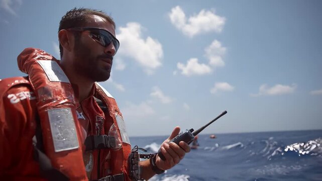 Medium shot of a maritime vessel officer using satellite paging systems to maintain communication across open seas under clear skies.