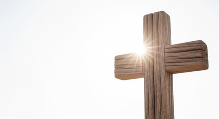Wooden cross with sunlight shining behind it in clear sky  