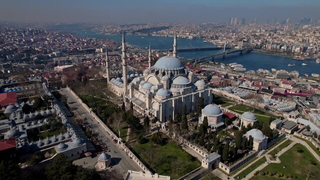 Aerial drone footage of S&uuml;leymaniye Mosque in Istanbul, featuring Ottoman architecture with domes and minarets, the Golden Horn, Halic Bridge, boats and the historic city skyline.