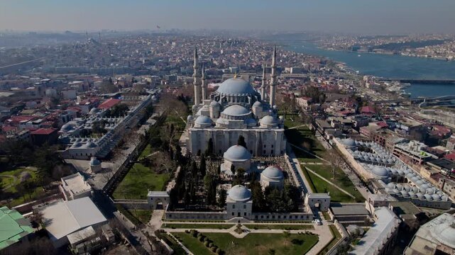 Aerial drone footage of S&uuml;leymaniye Mosque in Istanbul, featuring Ottoman architecture with domes and minarets, the Golden Horn, Halic Bridge, boats and the historic city skyline.