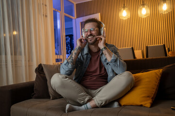 Obraz premium Handsome man listening to music with wireless headphones at home in cozy living room