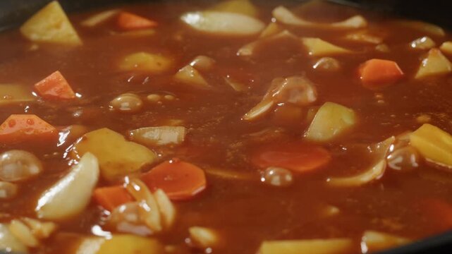 Hungarian goulash soup cooking close-up in pot, chef cook traditional polish or zech soup in restaurant. 