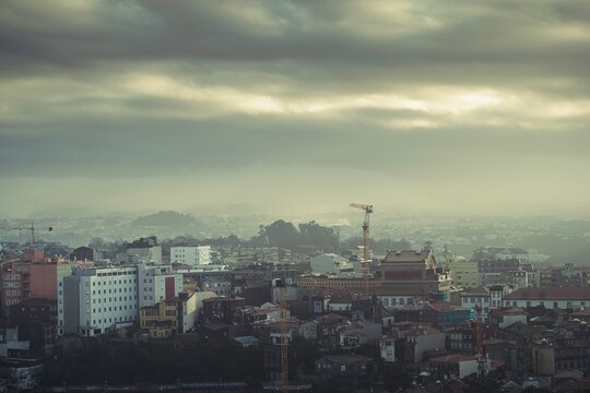 A mesmerizing view of Porto's cityscape reveals a blend of old and new architecture under a moody sky. The atmosphere pulses with the spirit of traditional Portuguese culture and emerging modernity