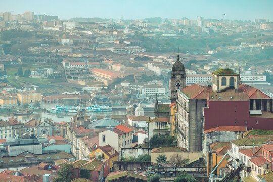 Stunning views of Porto reveal vibrant rooftops and winding streets, showcasing the Douro River and historic charm of the Ribeira District on a foggy morning