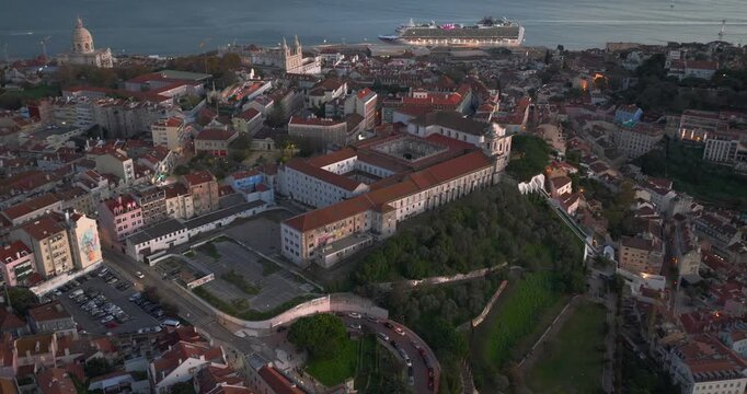 Wide aerial panorama across Lisbon Alfama and Graca districts and green hills with the city fading into the horizon under bright European daylight