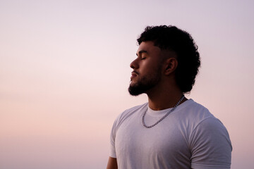 Young man relaxing with closed eyes during sunset