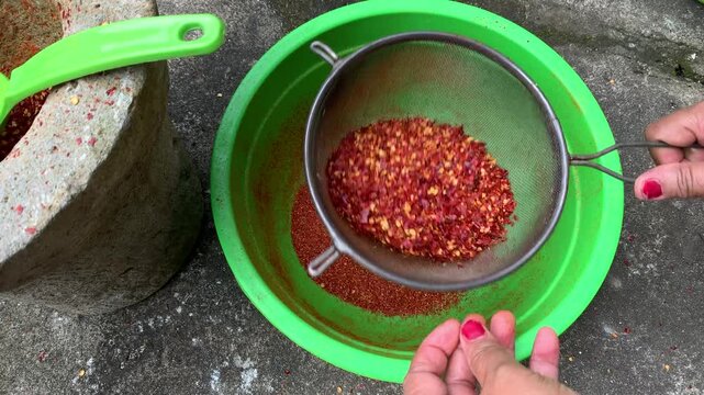 sifting dried hot peppers with strainer traditionally.