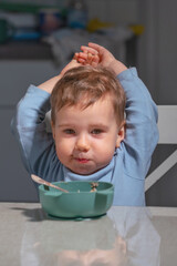 Fototapeta premium Toddler eating oatmeal with spoon while practicing coordination and independence.