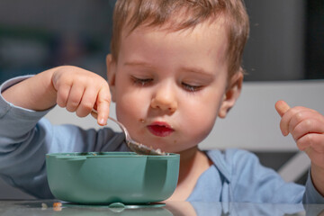 Toddler learning control and coordination during breakfast eating.