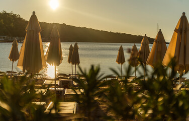 Empty sun loungers and umbrellas on the beach at sunset golden hour with sea view