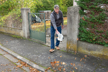 manual worker clean the fallen leaves on the road by blower