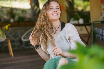 Portrait of a beautiful young woman with long blonde curly hair expressing calm joy.