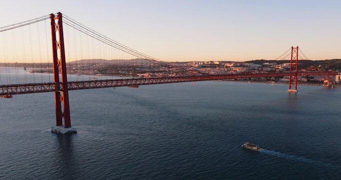 Wide drone view of 25 de Abril Bridge and Tagus River framed by Lisbon shoreline