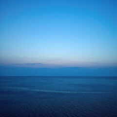 Fototapeta premium a large body of water stretching to the horizon, its calm surface reflecting soft, diffused light
