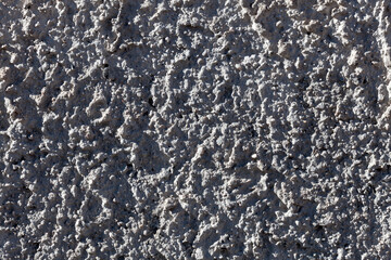 Irregular plaster surface with varied tones and rough aggregates, perfect for architectural materials and neutral textured backgrounds.